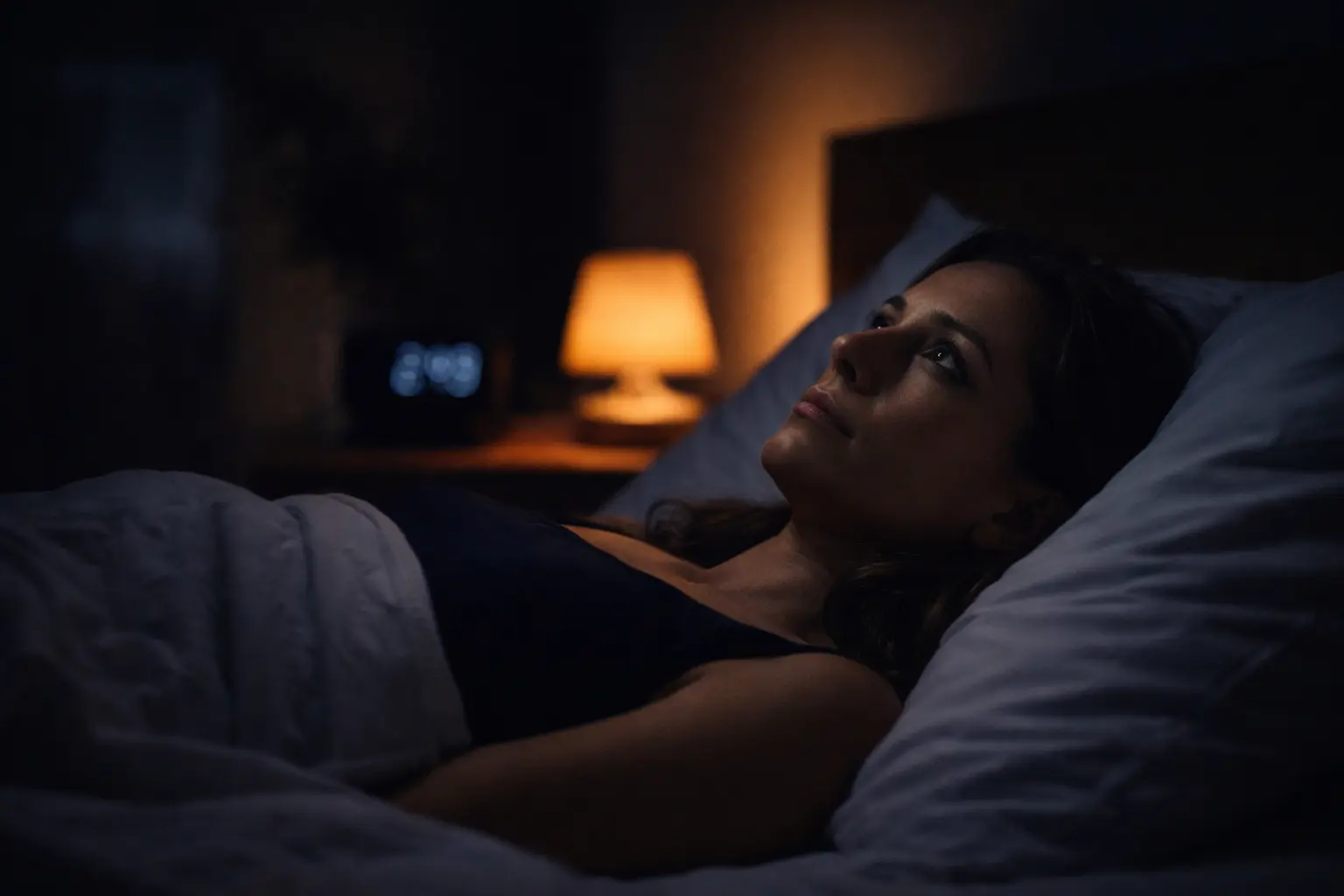 Personne éveillée dans le lit la nuit, regardant le plafond, ambiance douce et réaliste
